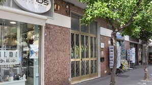 A storefront with a glass display window, a large brass door, and a tree in the foreground. - Vera Gioia Rooms de Charme (Sorrento)