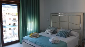 A hotel room with a bed, a window with curtains, a view of buildings, and a balcony. - Vera Gioia Rooms de Charme (Sorrento)
