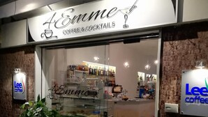 The exterior of a coffee and cocktail shop named 'Emme' with a glass display case and potted plants outside. - Vera Gioia Rooms de Charme (Sorrento)