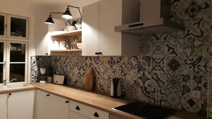 Una cocina con salpicadero estampado, armarios blancos y encimera de madera.