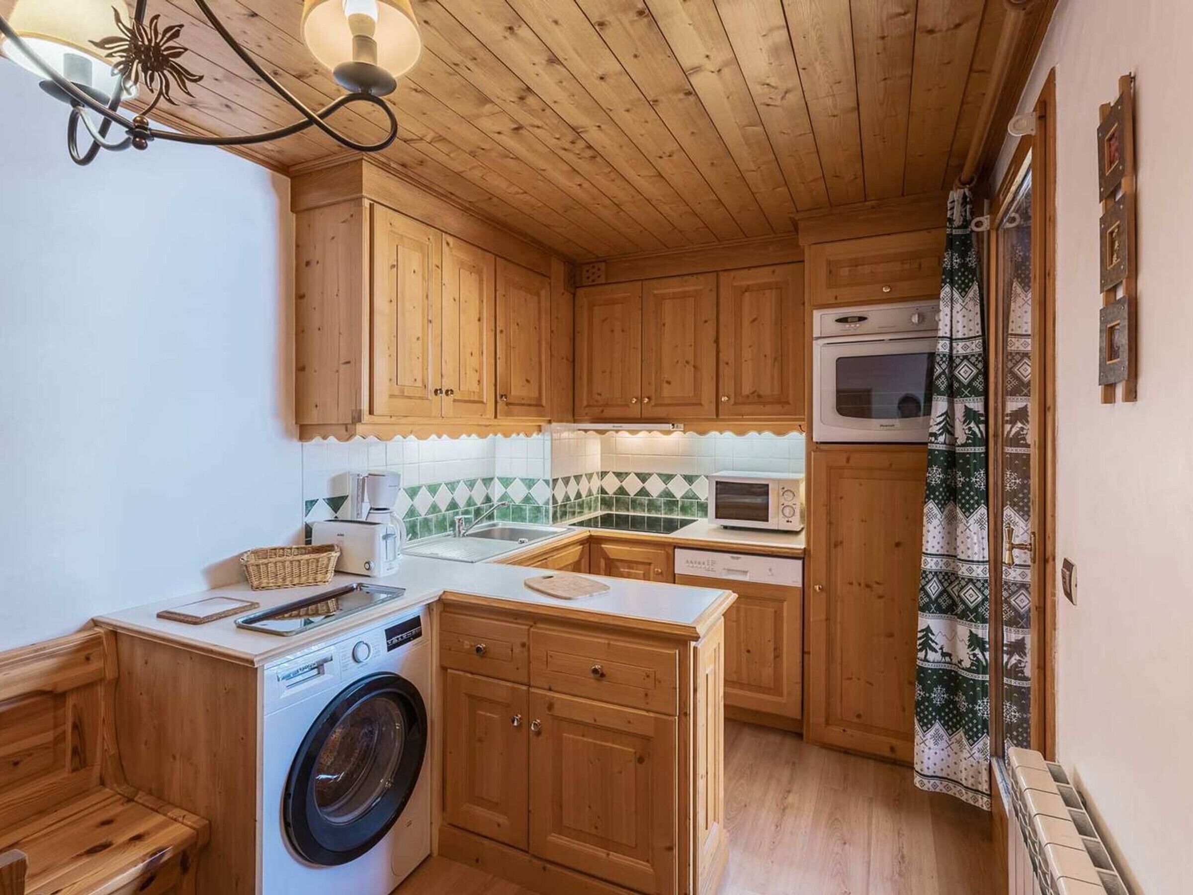 Una cocina compacta con armarios de madera, lavadora, microondas y cafetera.