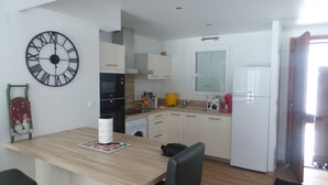 Une cuisine de taille réduite avec des meubles blancs, un four à micro-ondes, un évier et une grande horloge murale.