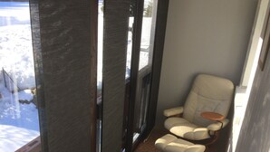 Un couloir donnant sur un paysage enneigé grâce à de grandes fenêtres, et menant à un espace détente avec deux fauteuils et une petite table.
