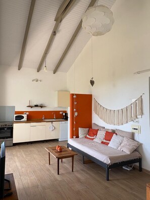 A modern living room with a sofa, a coffee table, a kitchen area with appliances, and a dining table. - villa MANGO any comfort with small sea view (Capesterre de Marie-Galante)