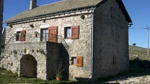 Ein Gebäude aus Stein mit Satteldach, einem kleinen Balkon und einem Schornstein.