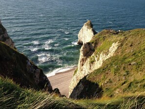 A coastal landscape with cliffs, a beach, and the sea.