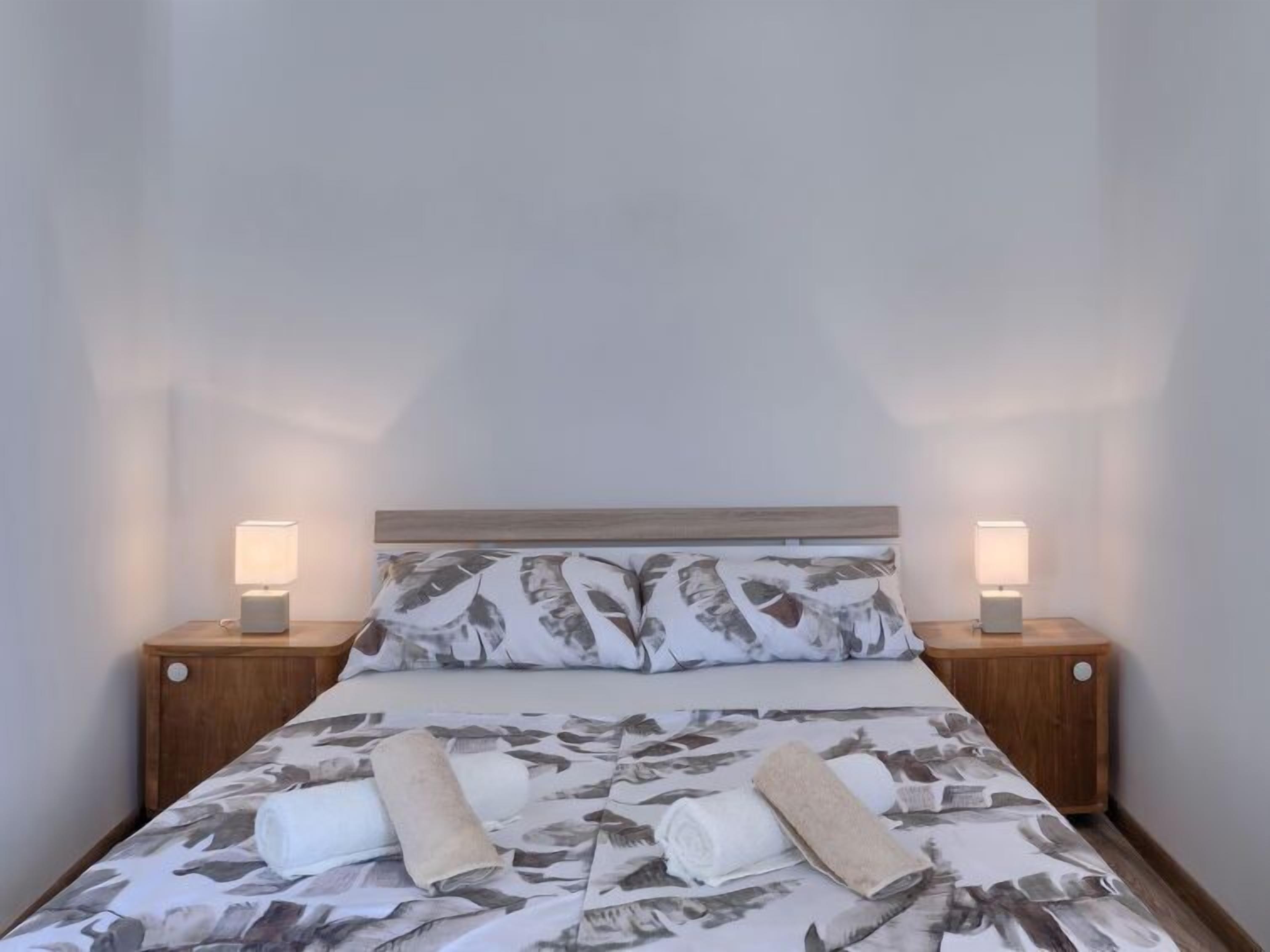A neatly made bed with a floral-patterned bedspread and two bedside lamps on wooden nightstands.