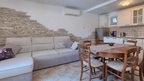 Ein gemütlicher Wohnbereich mit einer Couch, einem Esstisch mit Stühlen und einer Küche mit Schränken und Geräten.