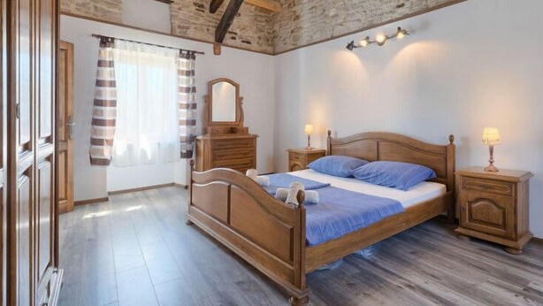 Ein Schlafzimmer mit einem hölzernen Bett, einem Schminktisch, einem Spiegel und einem Nachttisch mit Lampen.