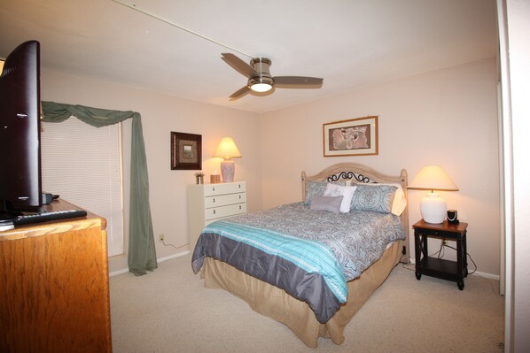 A bedroom with a bed, a ceiling fan, a dresser, a TV, and two bedside lamps. - Camelot Golf Course - Comfortable 2 bedroom (Mesa)