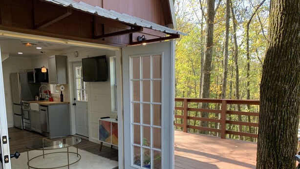 A wooden deck with a glass door leading to a kitchen area.