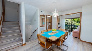 Een eetgedeelte met een tafel, stoelen en een kroonluchter.