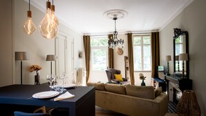 A modern living room with a sofa, dining table, and chandelier. - Elisabeth's suite in the heart of the medieval center of Sarlat (Sarlat-la-Canéda)