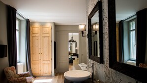 A bathroom with a large mirror, a sink, and a chair. - Elisabeth's suite in the heart of the medieval center of Sarlat (Sarlat-la-Canéda)