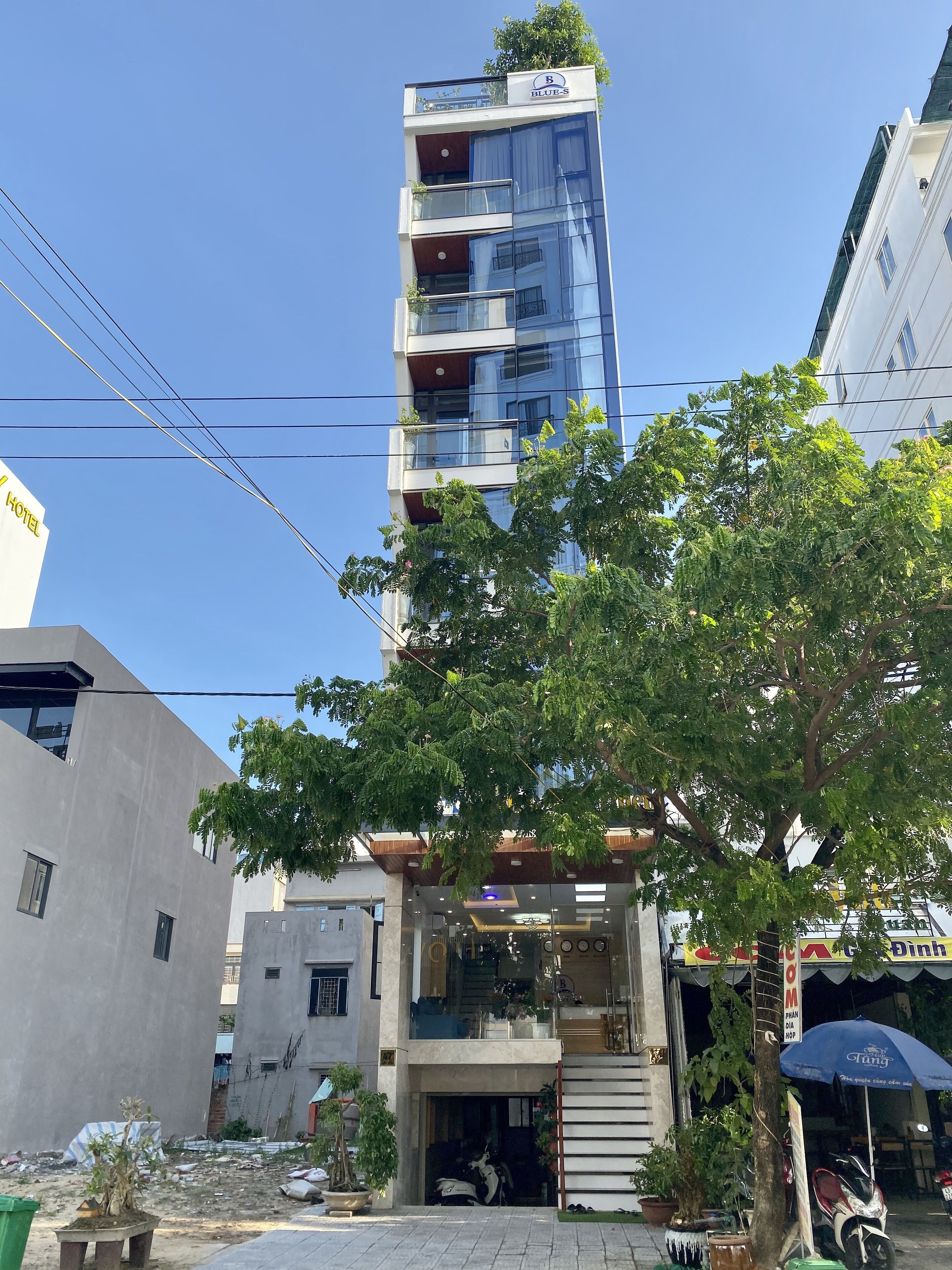 Un hotel moderno con facciata in vetro, diversi balconi e un ingresso ben visibile.