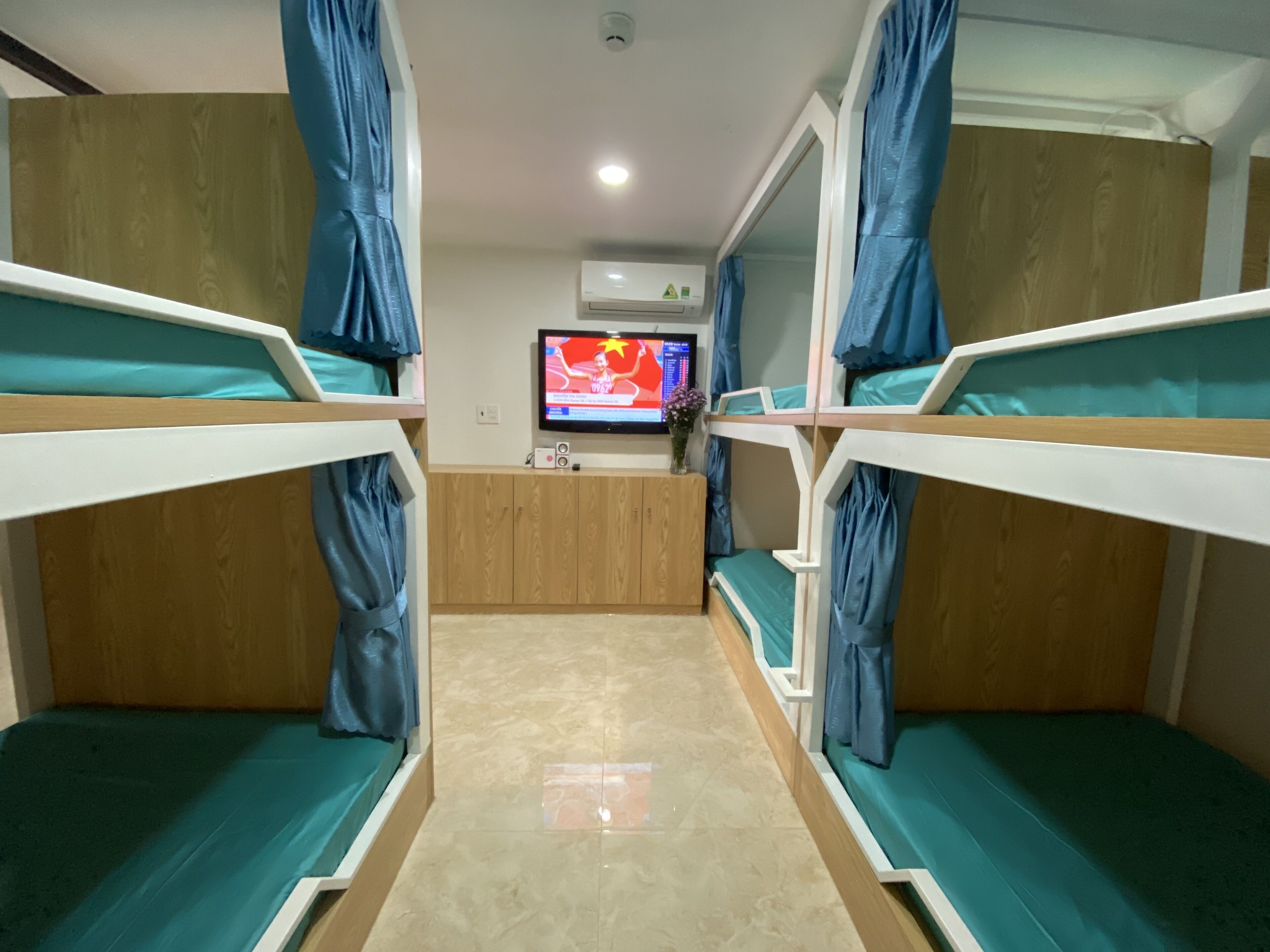 A bunk room with two bunk beds, a wooden desk, a television, and a wall-mounted air conditioner.