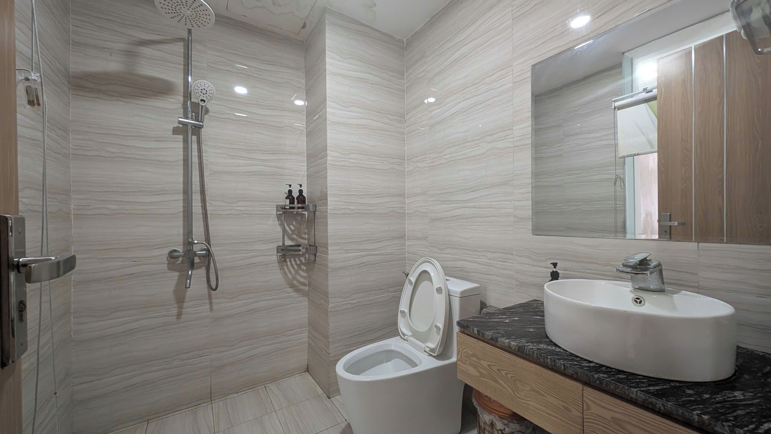 Un baño moderno con ducha, inodoro, lavamanos y espejo.
