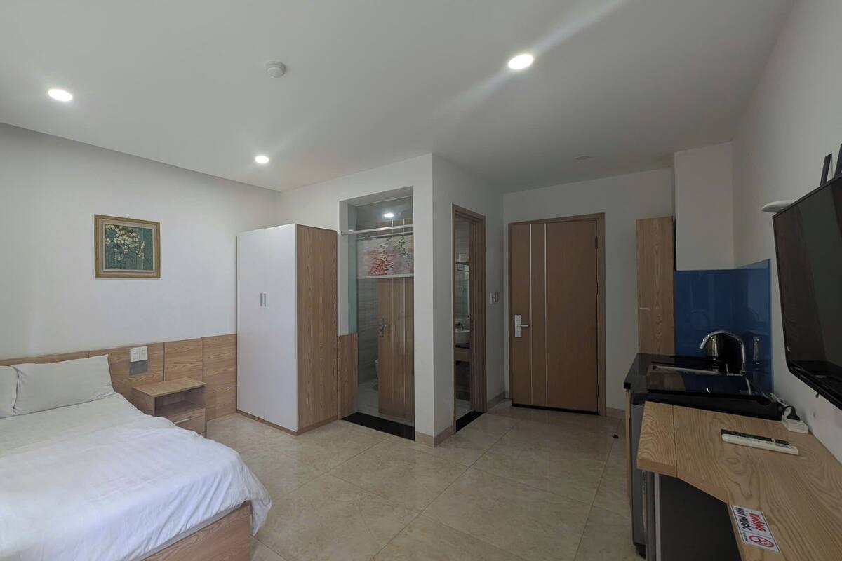 A hotel room with a bed, a desk, a TV, and a bathroom door.