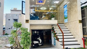 Um edifício moderno com entrada de vidro, uma scooter estacionada na frente e uma escadaria que leva ao andar superior.
