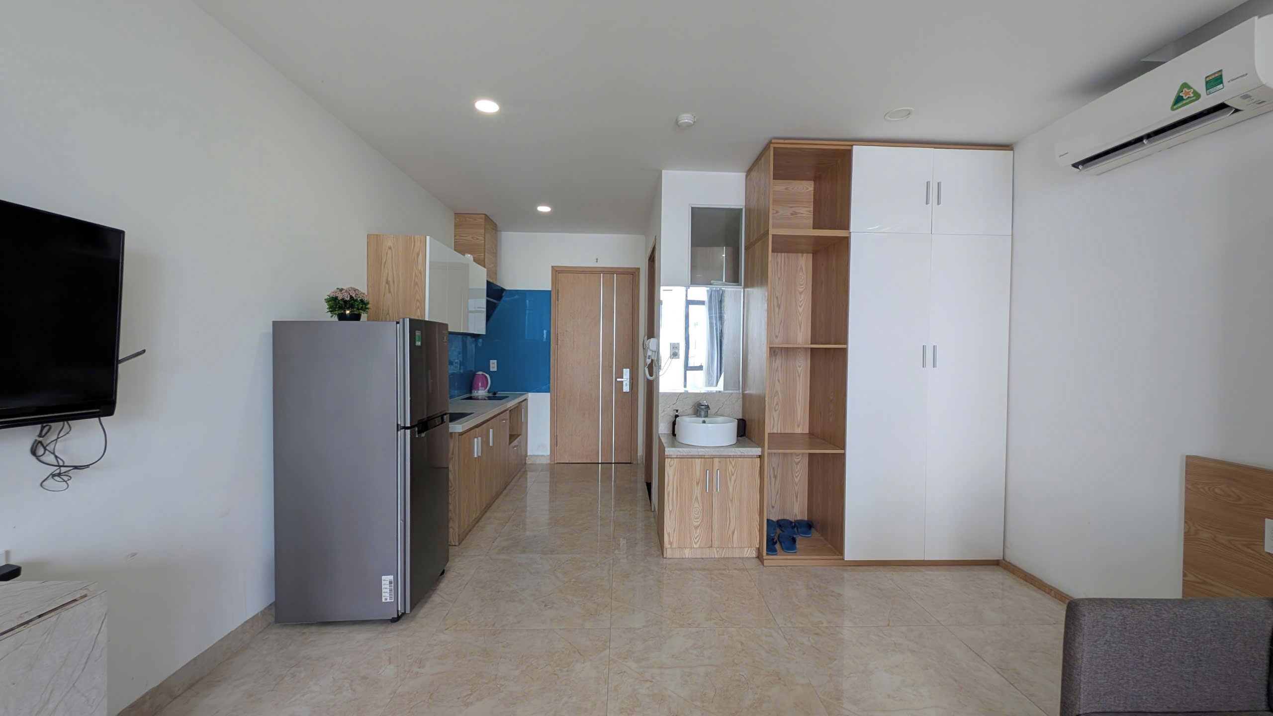 Una cocina moderna con refrigerador, televisor y armarios de madera.