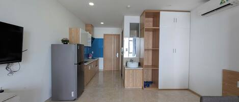 Una cocina moderna con refrigerador, televisor y armarios de madera.
