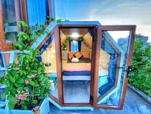 A compact, octagonal room with a bed, a small table, and a chair. - Blue S Hotel & Apartment (Da Nang)