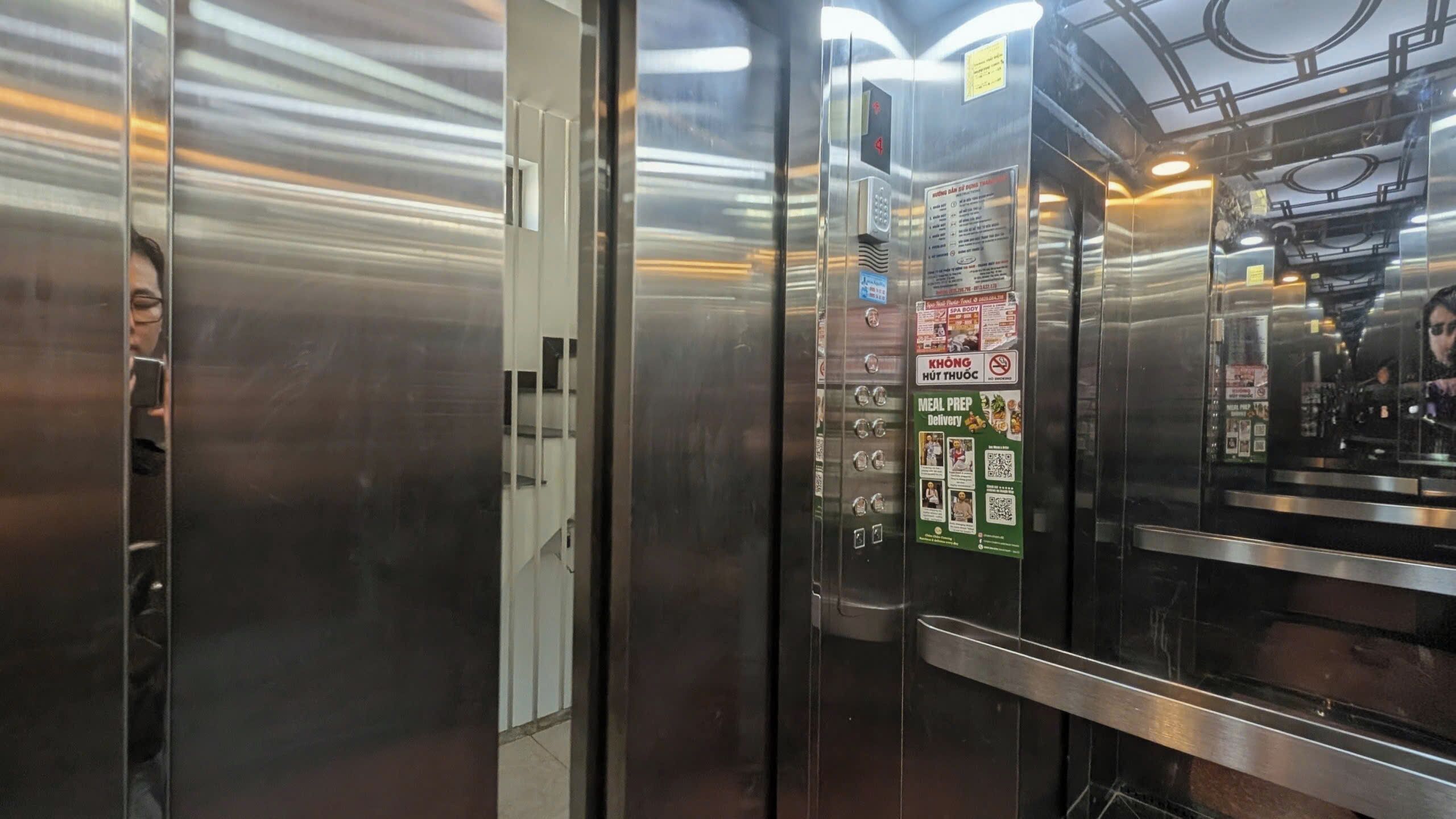 Un ascensor con puertas de acero inoxidable y un panel de visualización digital que muestra anuncios.