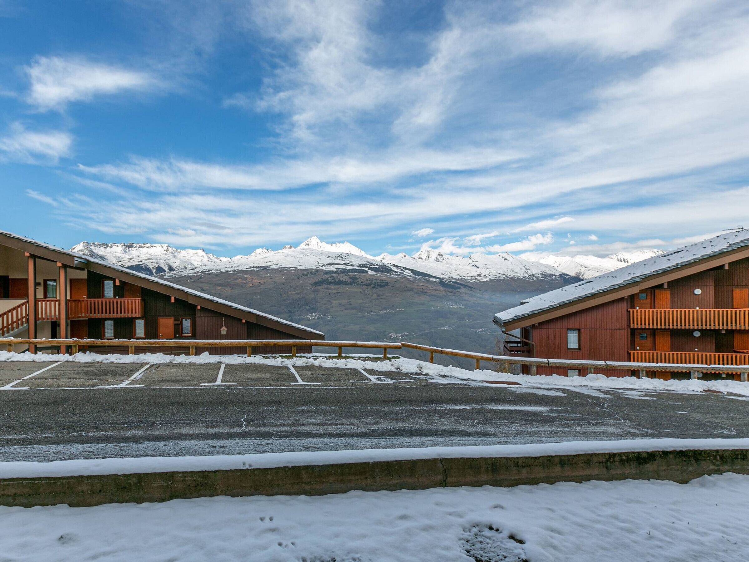 Hotel com estacionamento coberto de neve e vista para a montanha.