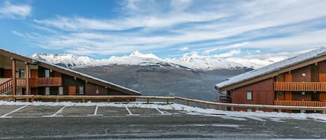 Hotel com estacionamento coberto de neve e vista para a montanha.