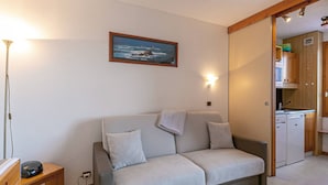 A cozy living room with a grey sofa, a small wooden table, and a painting of a coastal scene. - 2-room apartment, 4 people, pets allowed, Mont Blanc view (La Plagne-Tarentaise)