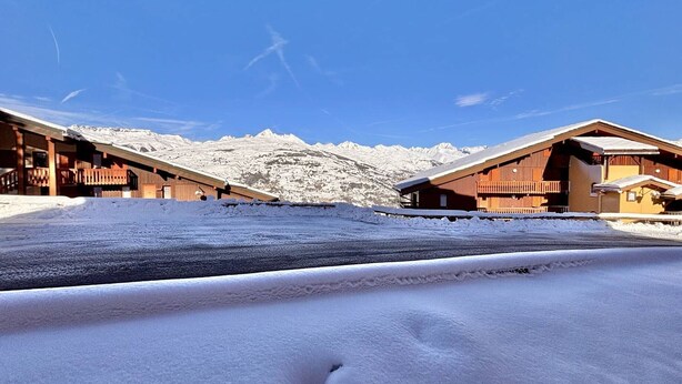 A snow-covered mountain landscape with wooden buildings, a clear sky, and a visible footprint in the snow. - 2-room apartment, 4 people, pets allowed, Mont Blanc view (La Plagne-Tarentaise)