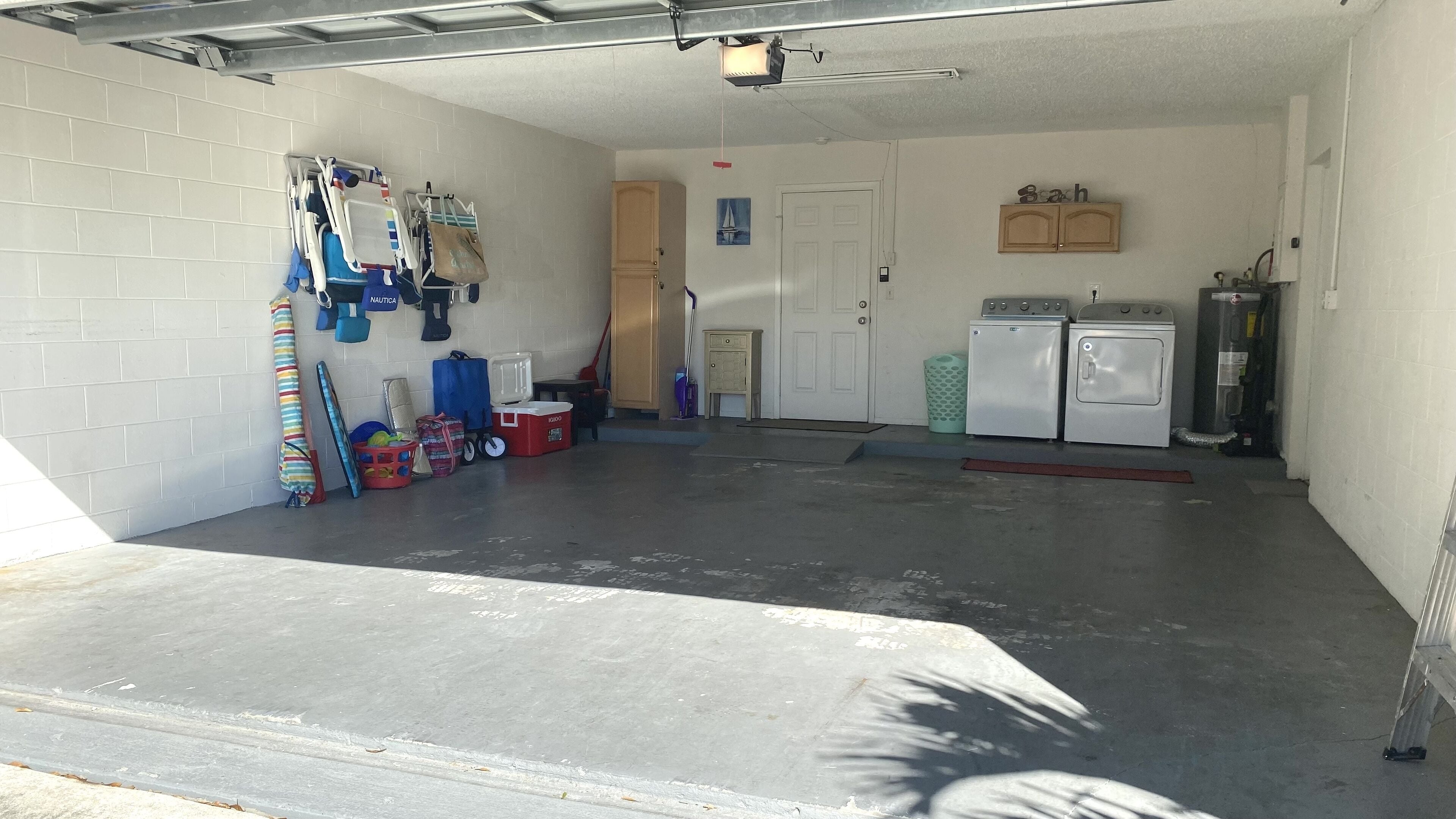 A garage with a concrete floor, a door, and a washing machine.