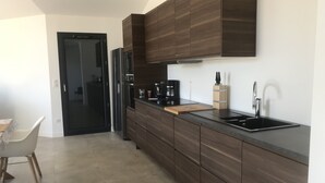 A modern kitchen with dark wood cabinets, a black refrigerator, a coffee maker, and a sink. - Villa Rossa, Contemporary Heated pool  (PALASCA)