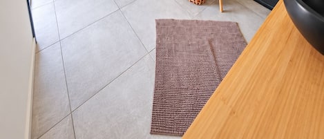 Un dormitorio con cama, mesita de noche, lámpara colgante y zona de ducha con puerta de cristal.