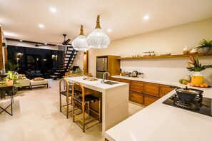 A modern kitchen with a central island, wooden cabinets, and pendant lighting.