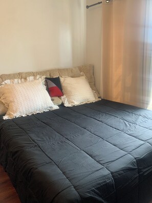 A bed with a dark quilt, two pillows, and a headboard.