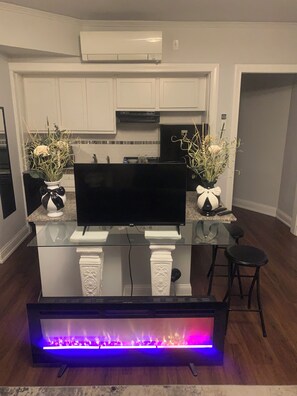 A modern kitchen with white cabinets, a black countertop, and a flat-screen TV.