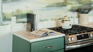 A kitchen with a gas stove, a green cabinet, and a wall-mounted vent hood.