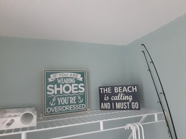 Dos letreros en una pared, uno dice “Si llevas zapatos, estás demasiado elegante” y el otro reza “La playa me llama y debo ir”.