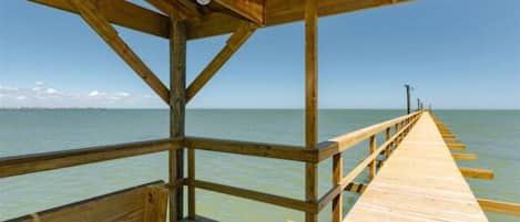 A wooden pier extending into calm waters with a clear sky above.
