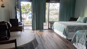 A hotel room with two beds, a desk, a chair, and a view of the outside. - Come on down for a great fishing and beach get away at Benjamin's Pier! (Rockport)