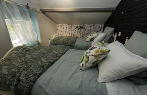 Una camera da letto con un letto a castello, un letto singolo e una finestra con tende leggere.