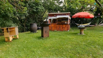Un espace extérieur rustique, avec une structure en bois, une poubelle et un hamac.