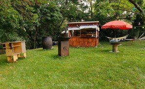 A rustic outdoor setting with a wooden structure, a trash bin, and a hammock.
