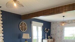 Un salon avec un canapé, une table, une chaise, une horloge, une lampe et une fenêtre.