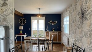 Un coin repas avec une table et des chaises en bois, un réfrigérateur, une horloge et un élément décoratif mural.