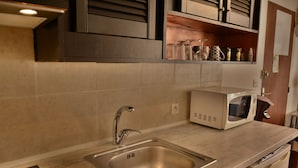 A kitchen with a stainless steel sink, a microwave, and a cabinet above the counter.