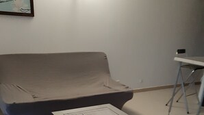 A room with a grey sofa, a small white table with a document on it, and a metal chair. - F2, air conditioned all comfort (Fréjus)