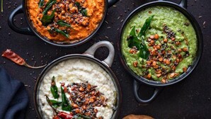 Three bowls of chutney with various spices and chilies, accompanied by a stack of white bread and a few fried snacks. - Hotel Sea Grand (Mumbai)