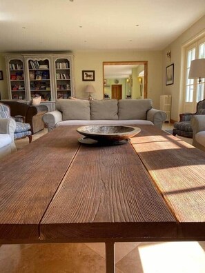 Ein Wohnzimmer mit einem großen Couchtisch aus Holz, einer Couch und einem Bücherregal.